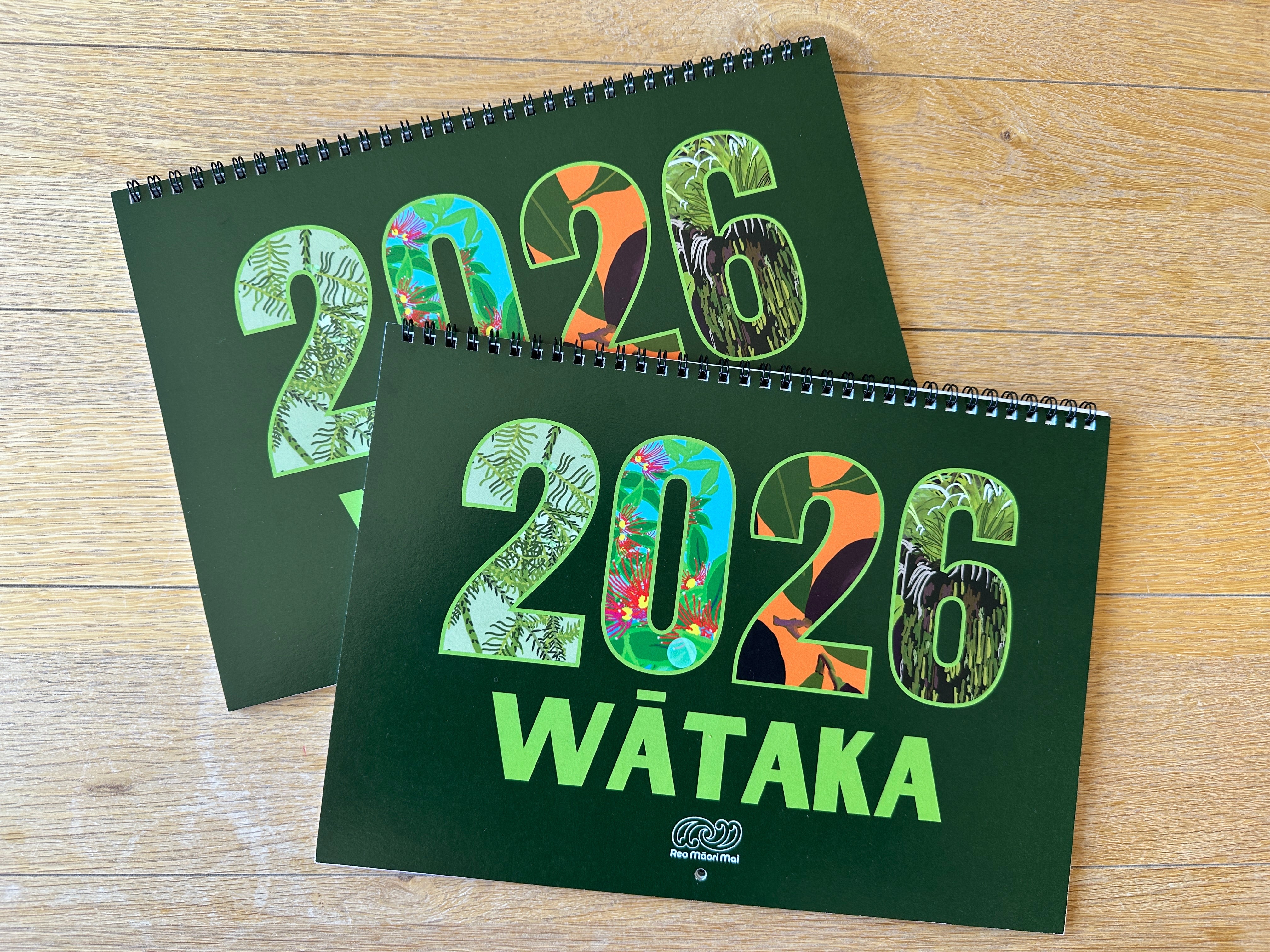 Two green calendars for 2026 on a wooden surface